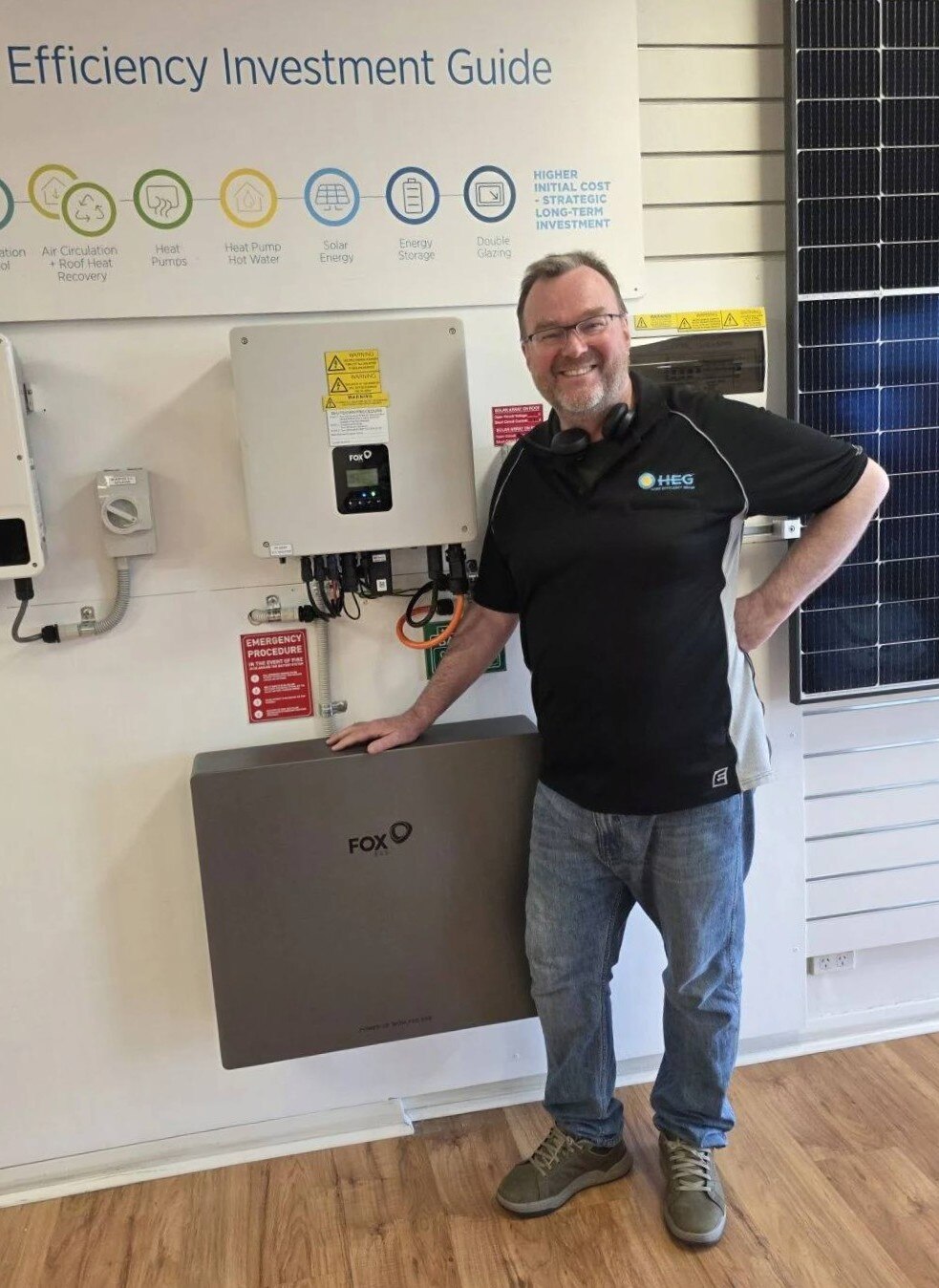Adam Hirst stands next to a white battery system.