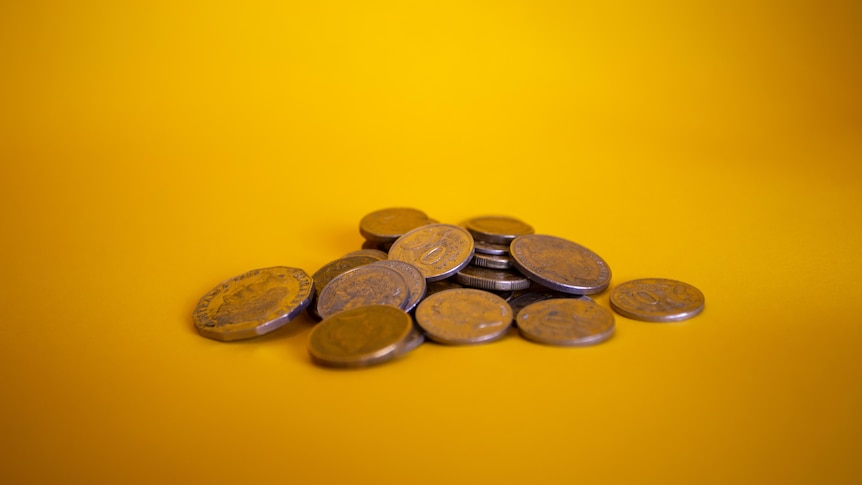 A pile of australian coins on a yellow backdrop.