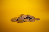 A pile of australian coins on a yellow backdrop.