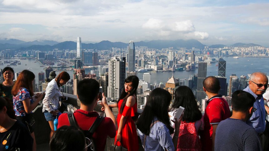 A woman poses for a photo at a lookout over Hong Kong harbour