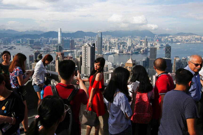 A woman poses for a photo at a lookout over Hong Kong harbour