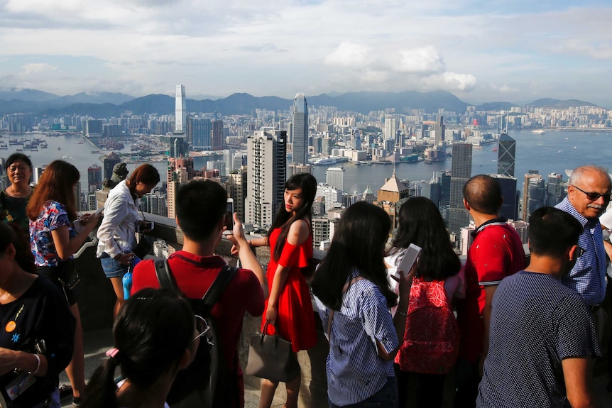 A woman poses for a photo at a lookout over Hong Kong harbour