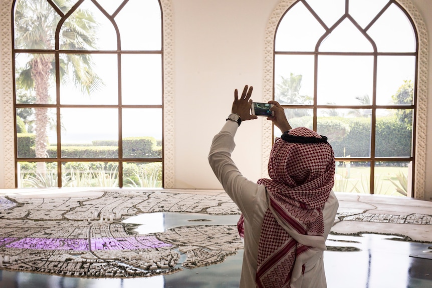 A man takes a photo of a scale model of King Abdullah Economic City.