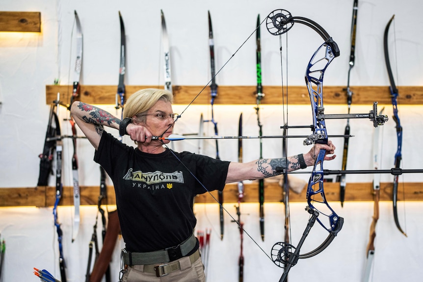 Ukrainian medic Yuliia Paievska pulls a bow and arrow, ready to shoot. 