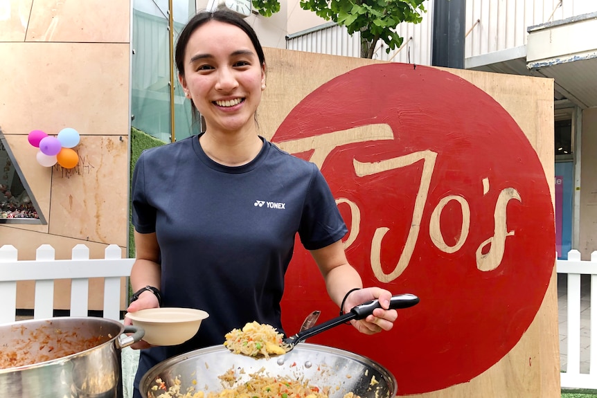 a young lady holds a lade of fried rice