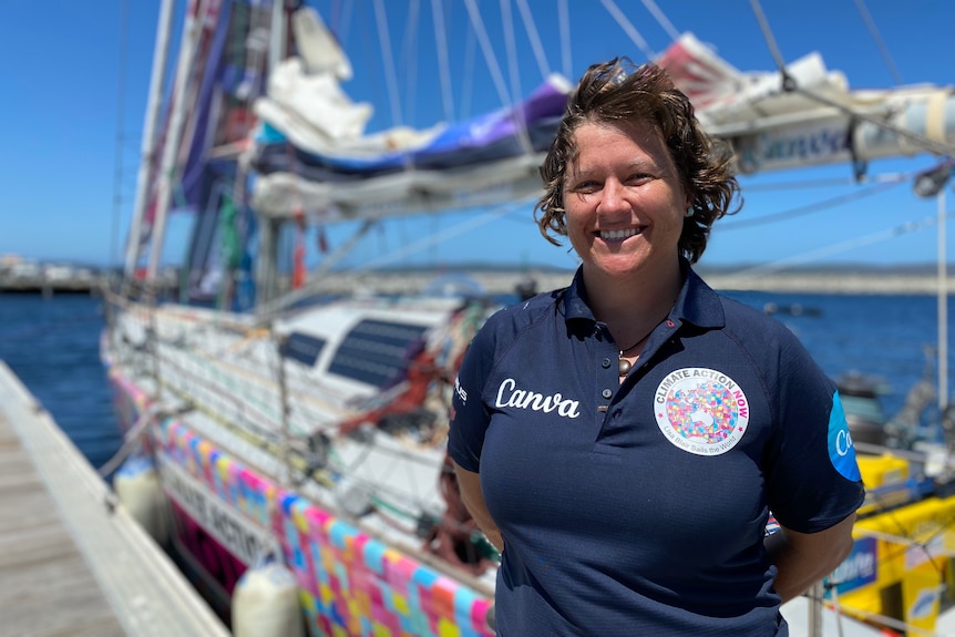 a woman stands in front of a yacht