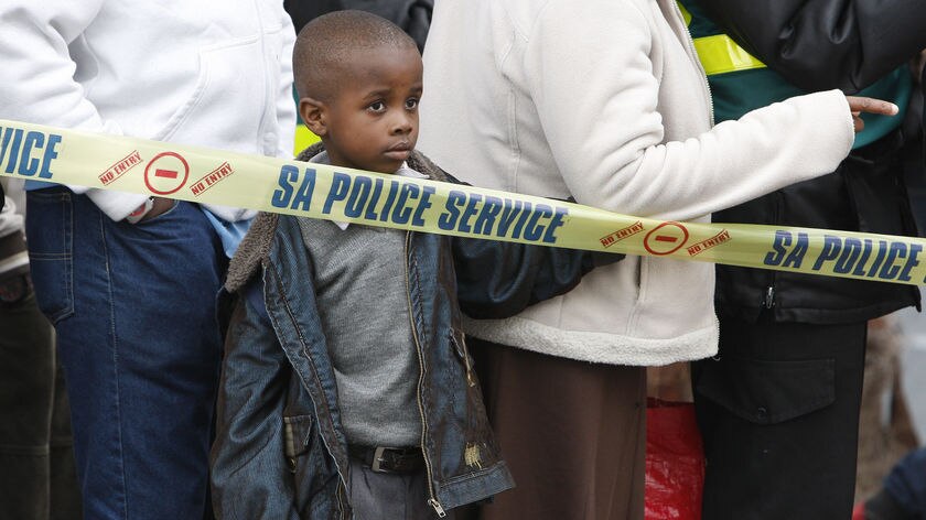 A child watches as police arrest six suspected armed robbers in central Cape Town