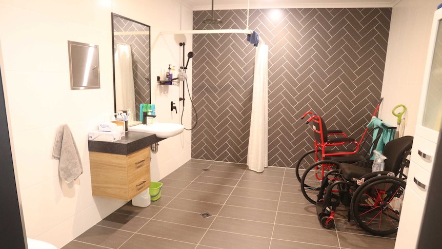 The interior of a bathroom with two wheelchairs inside