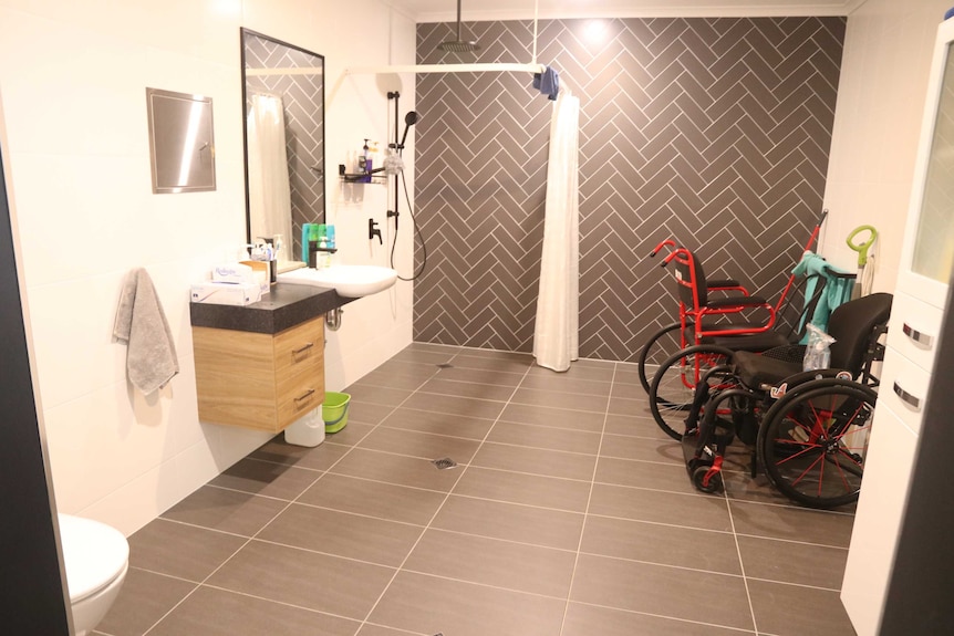 The interior of a bathroom with two wheelchairs inside.