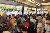Crowds of people, all wearing masks, at a train station