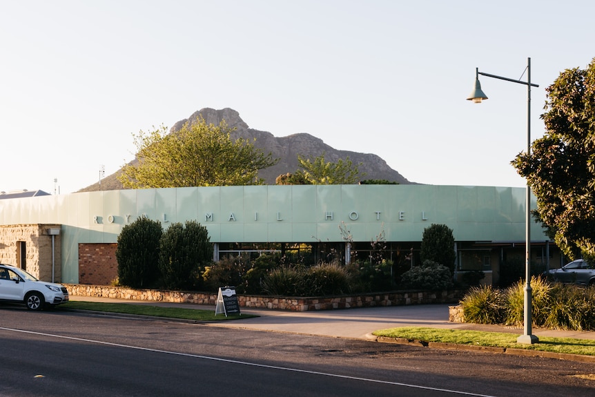 A fancy restaurant with rounded green metal frontage set in front of jagged Mountain