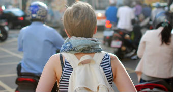 A woman travelling on her own navigates a busy street for ABC Life travel page.