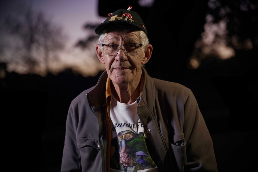 A man wearing a cap with mushrooms on it.