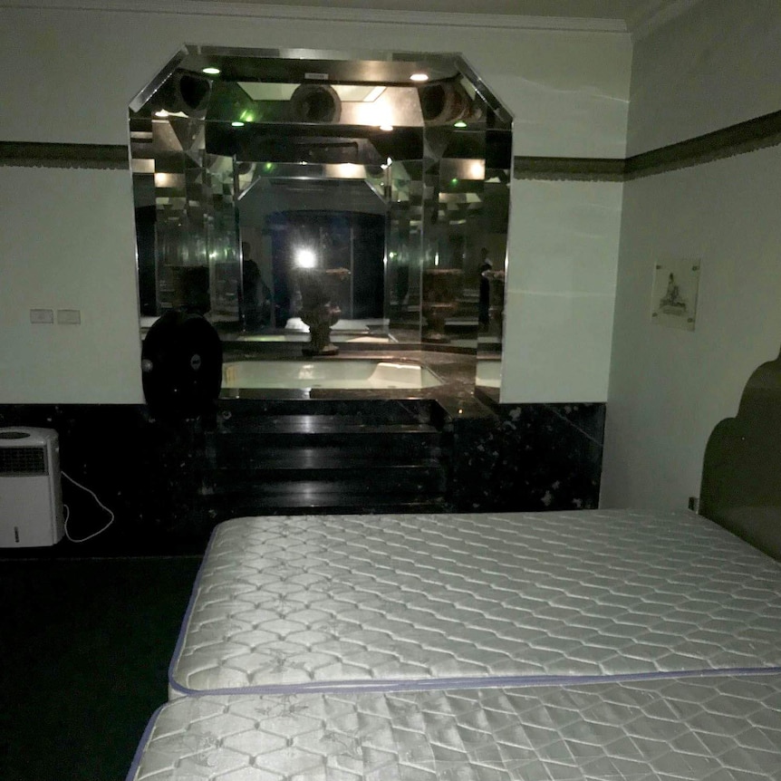 A large mirror adjacent to two unmade beds at the Wellbeing Planet.
