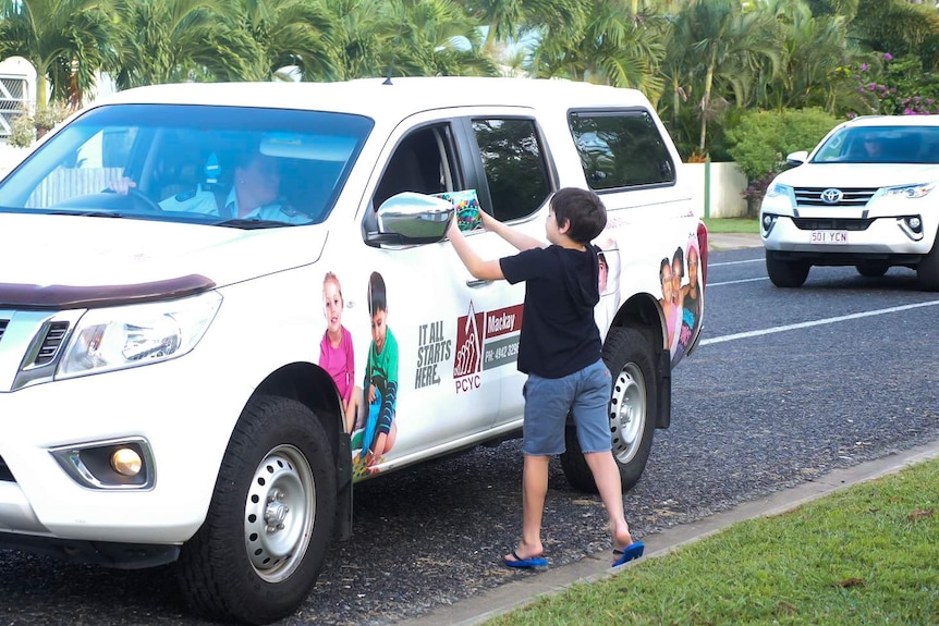 boy collects present from car parked on the side of a road