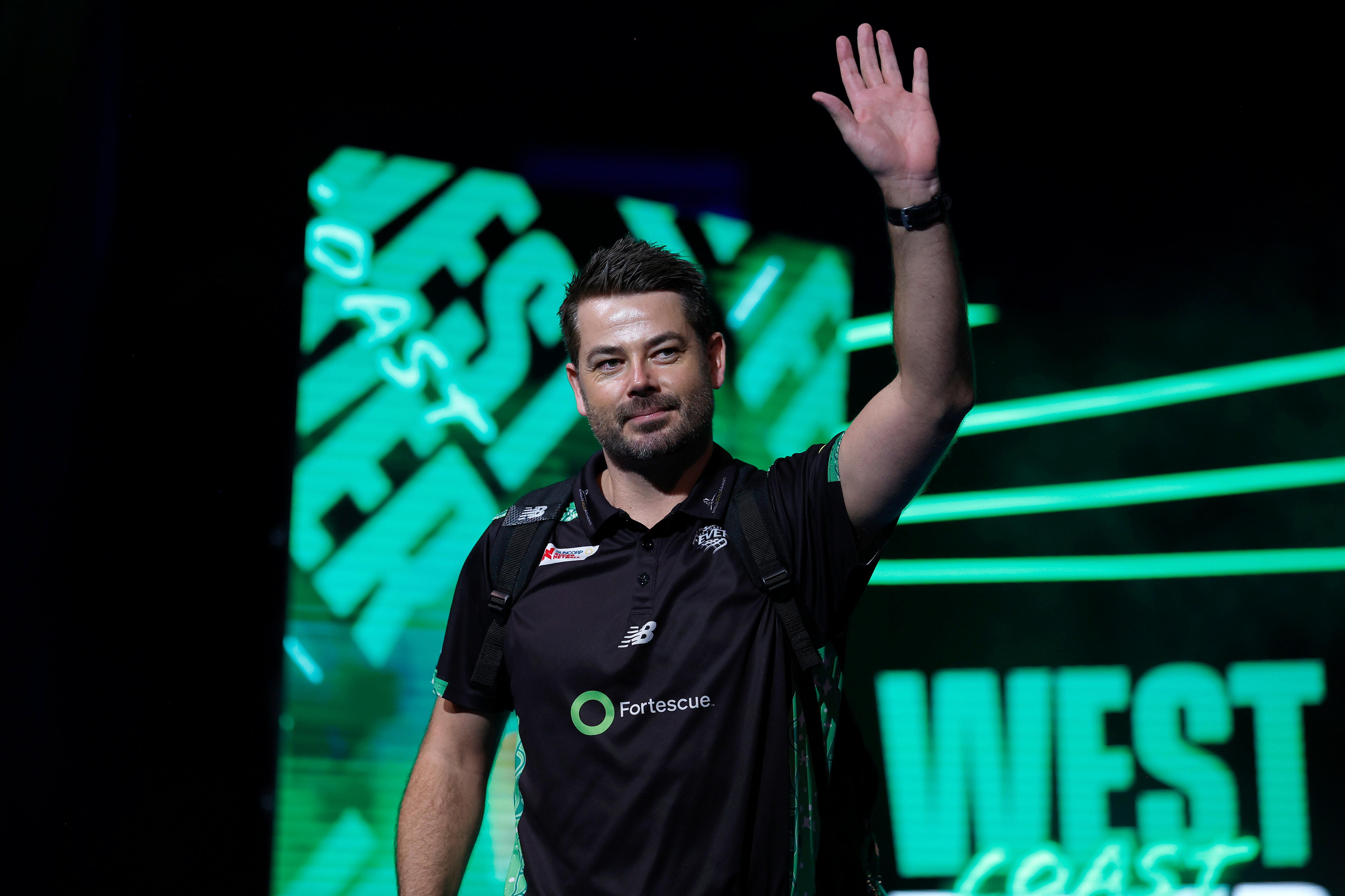 A coach waves as he walks into the arena