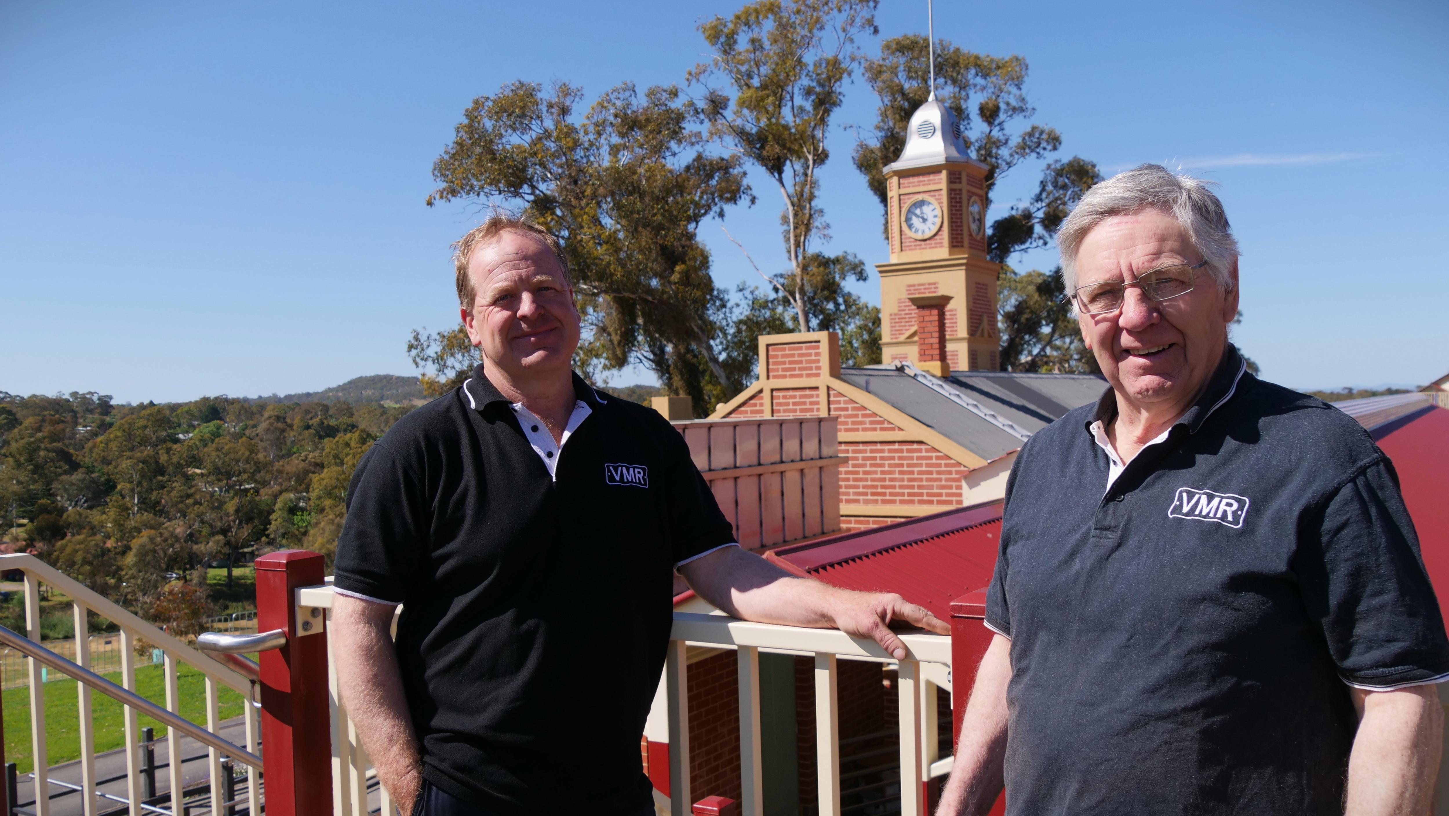Dos hombres se apoyan en una barandilla. 
