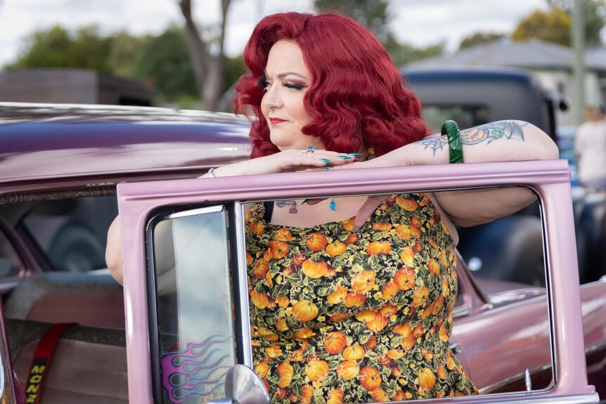 woman with red hair next to open car door