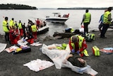 A wounded woman is treated after leaving Utoya island (in the distance)