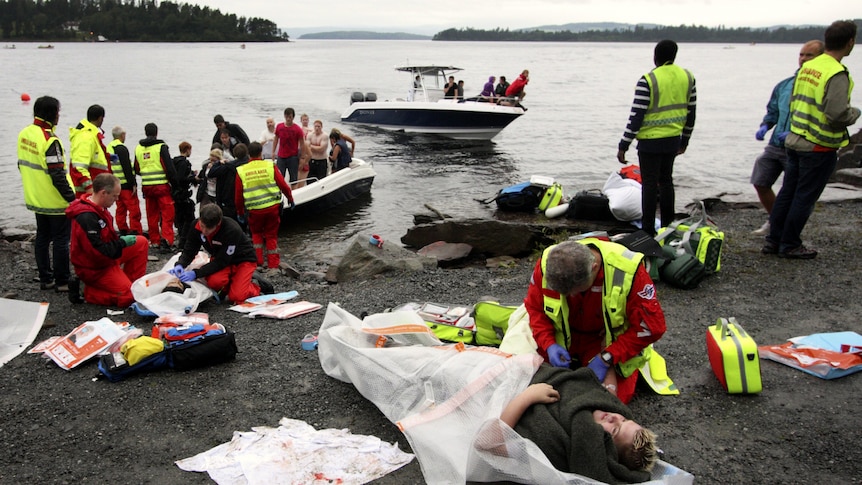 A wounded woman is treated after leaving Utoya island (in the distance)