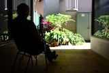 Silhouetted man sitting in a chair looking at garden