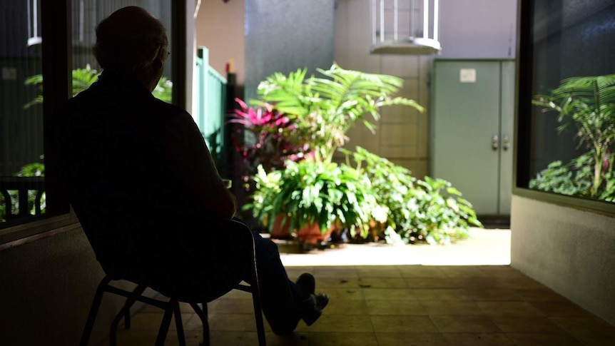 Silhouetted man sitting in a chair looking at garden