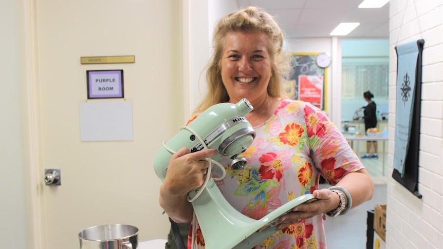 A woman holding a teal-green kitchen mixer