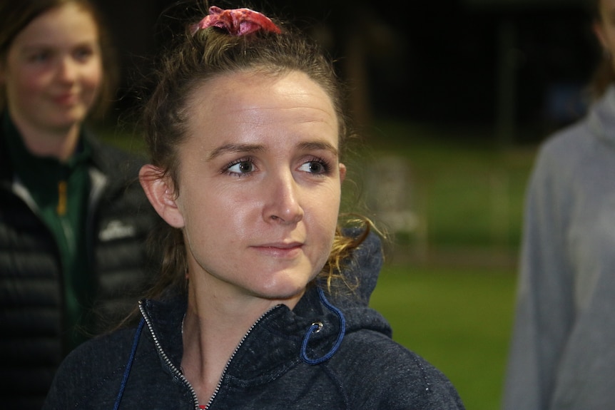 A close up portrait of a woman on a soccer field with her brown hair tied back