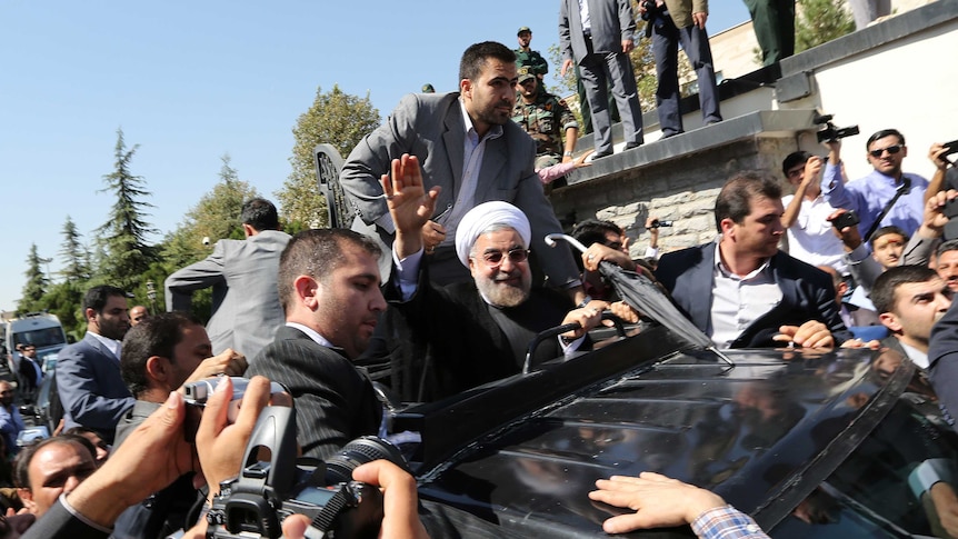 Iranian president Hassan Rouhani waves to supporters as his motorcade leaves Tehran's Mehrabad Airport.