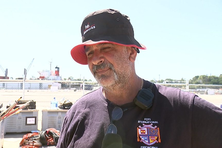 a man wearing a cap talking to the media outdoors