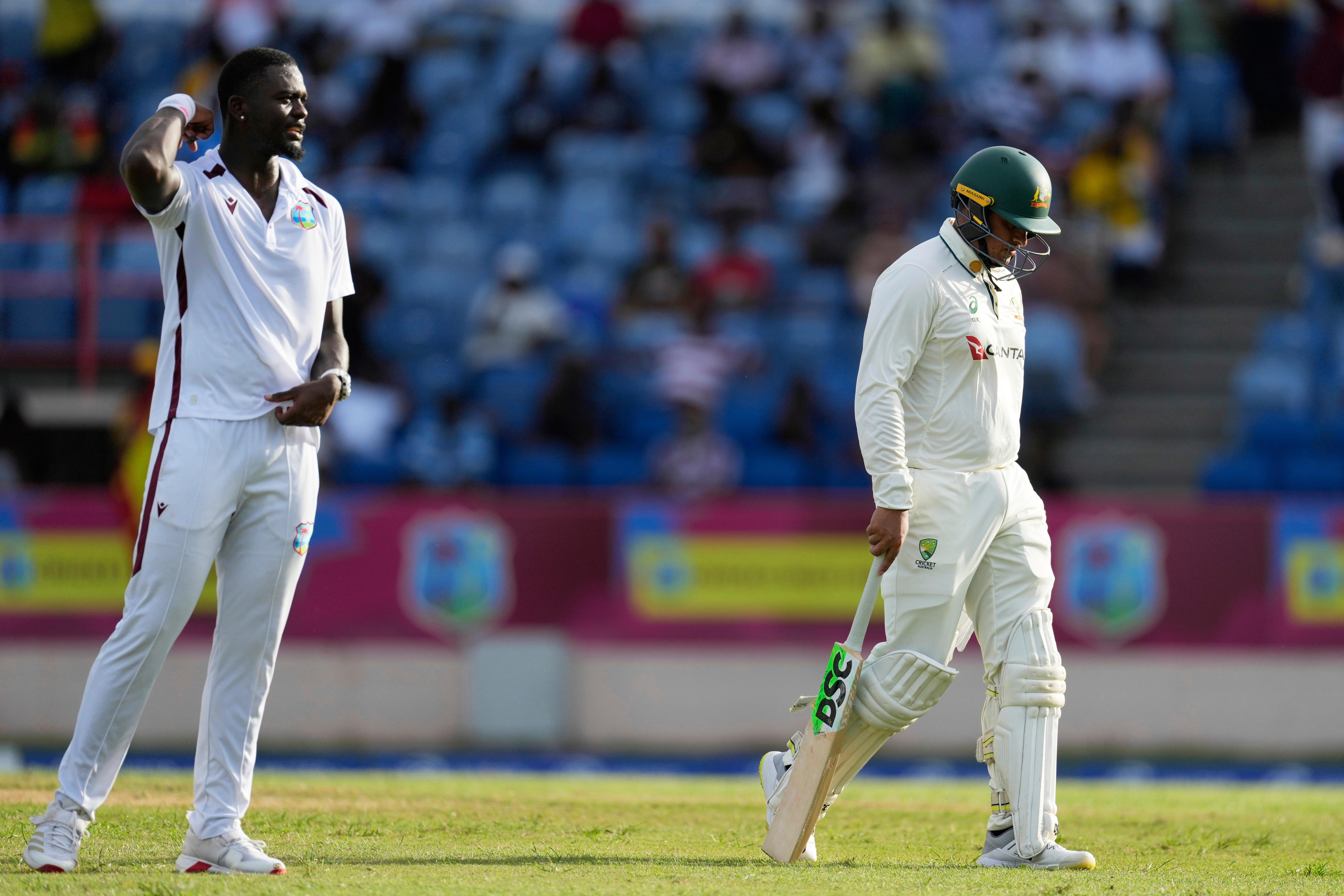 A cricketer walks off the field in fading light.