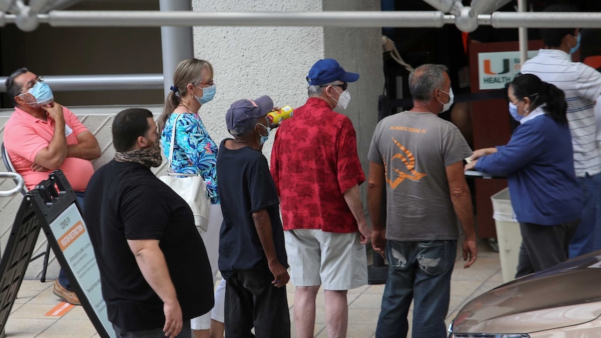 People wait in a queue outside a hospital in Miami, United States.