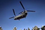 A UH-47 Chinook helicopter lands over US soldiers and Afghan National Army soldiers