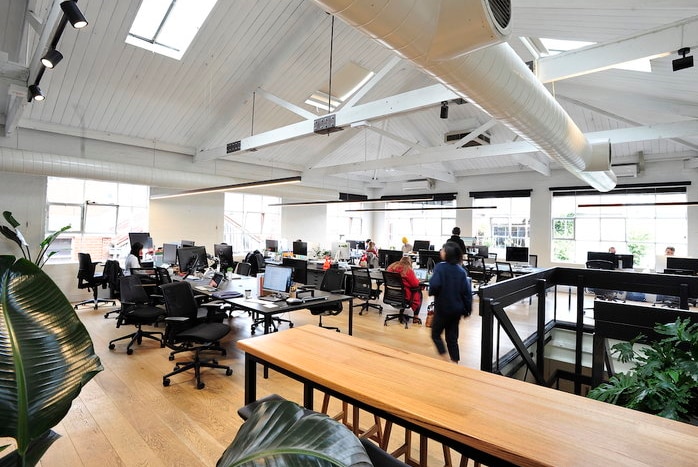 An open plan office with timber floors and high white ceiling.