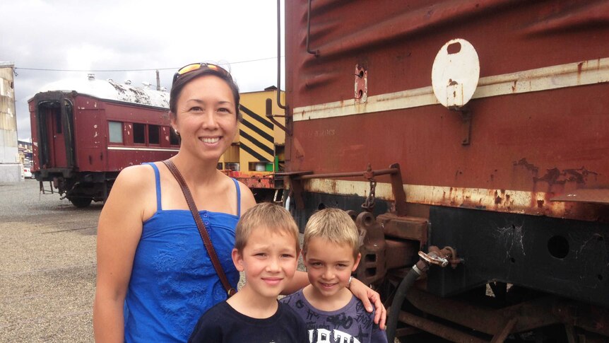 Kathy and her sons pose in front of a decommissioned train.