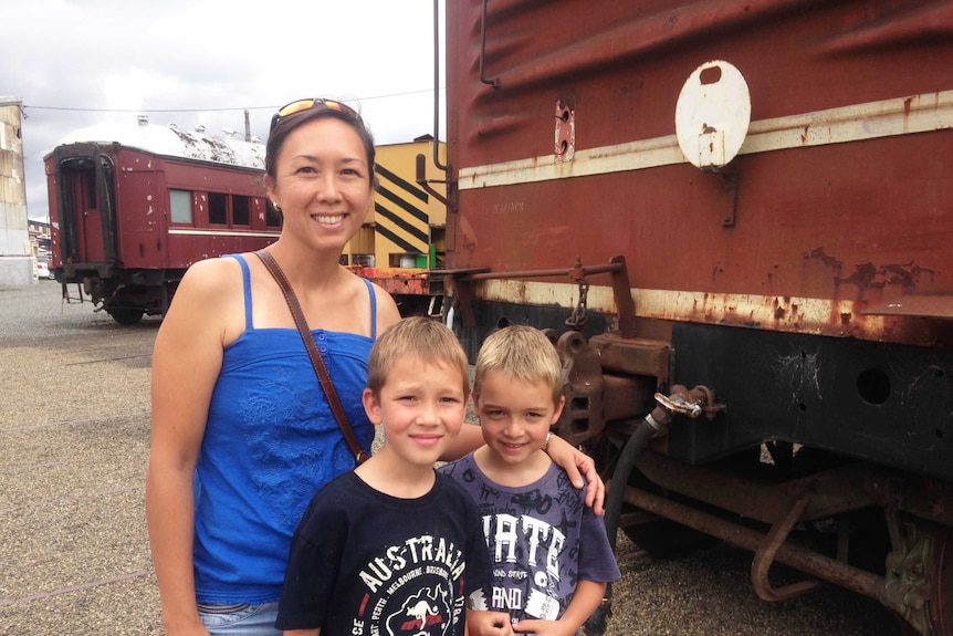 Kathy and her sons pose in front of a decommissioned train.