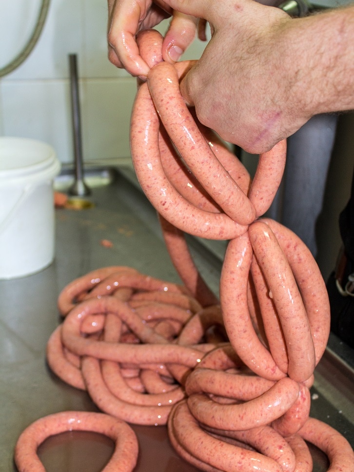 A man's hands hold a string of sausages