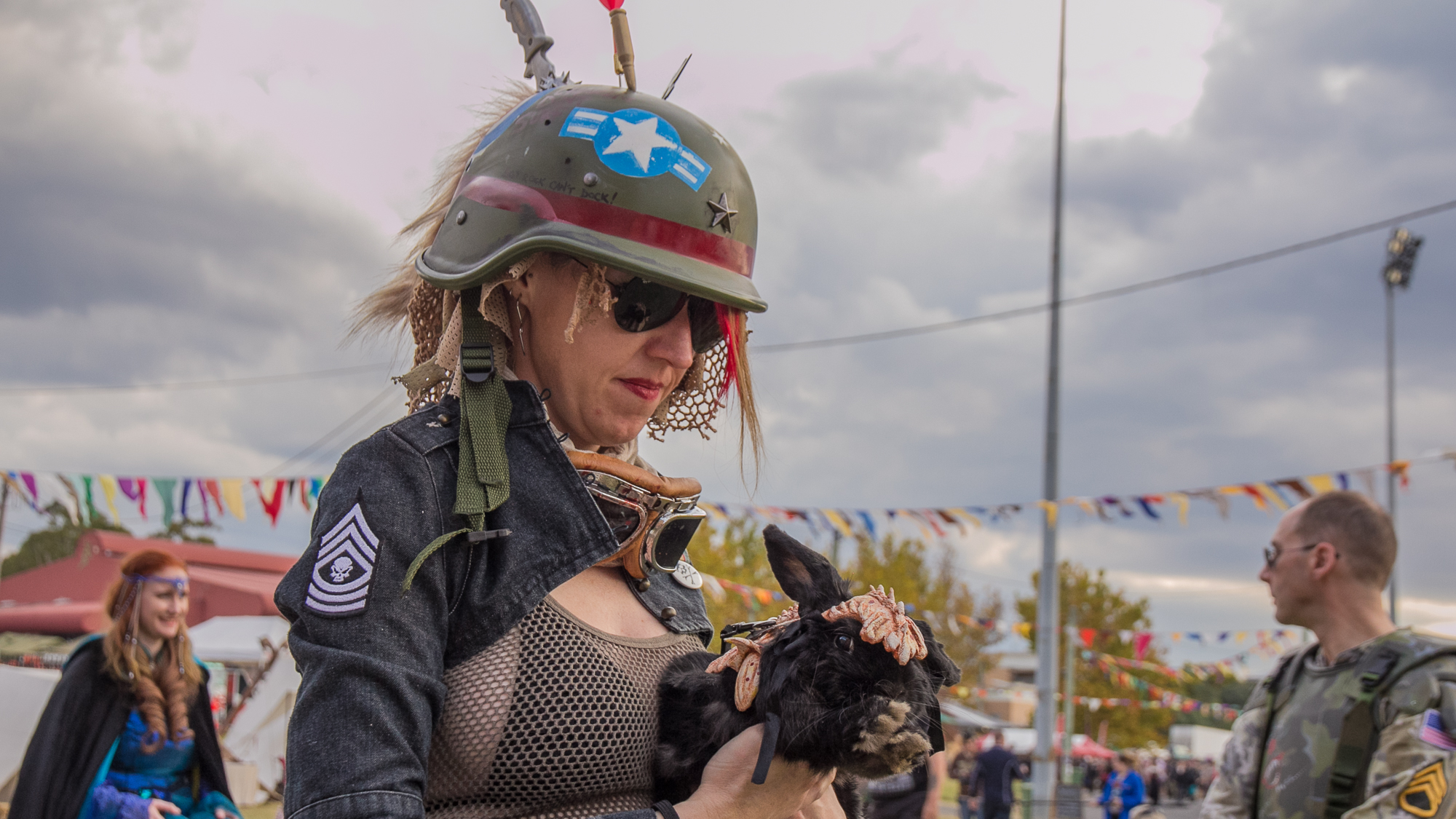 A woman in army gear wtih a rabbit with some armour on it