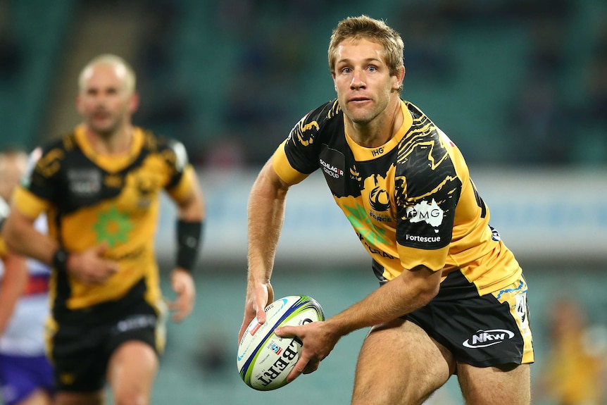 A Western Force Super Rugby AU player prepares to pass the ball with both hands against the Waratahs at the SCG.