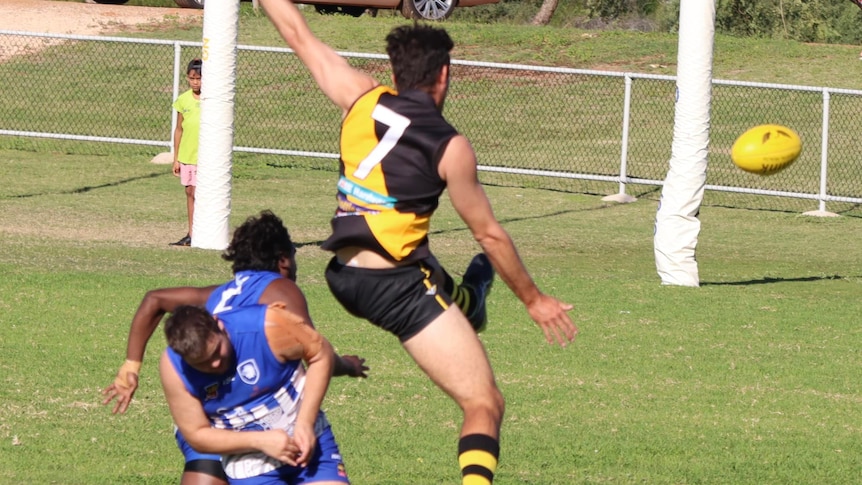 A man is mid jump after kicking a football