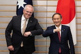 Scott Morrison bumps elbows with Yoshihide Suga. They are smiling.