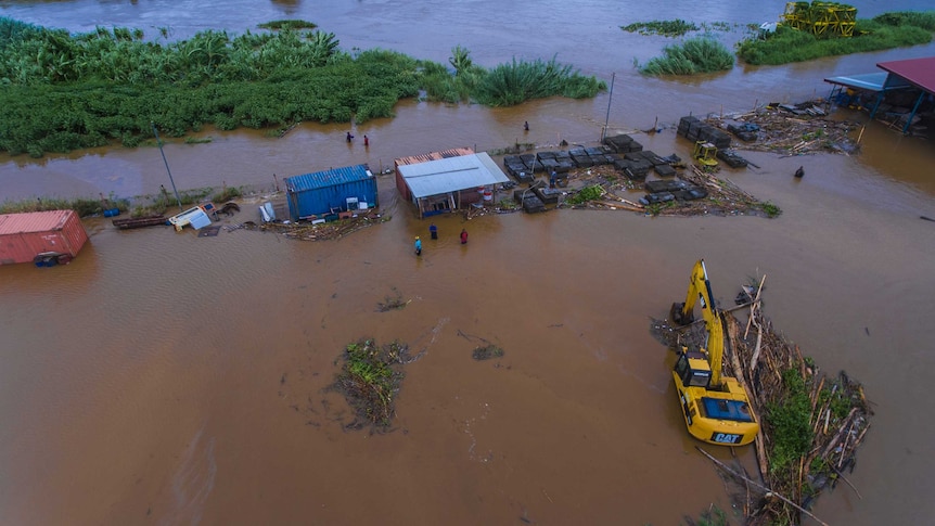 Aerial shot of people in water near a river that has burst its banks in Fiji.