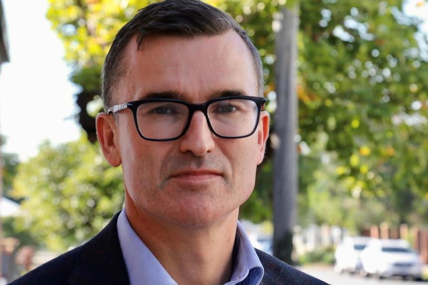 A close-up photo of WA Housing Minister John Carey with trees in the background.