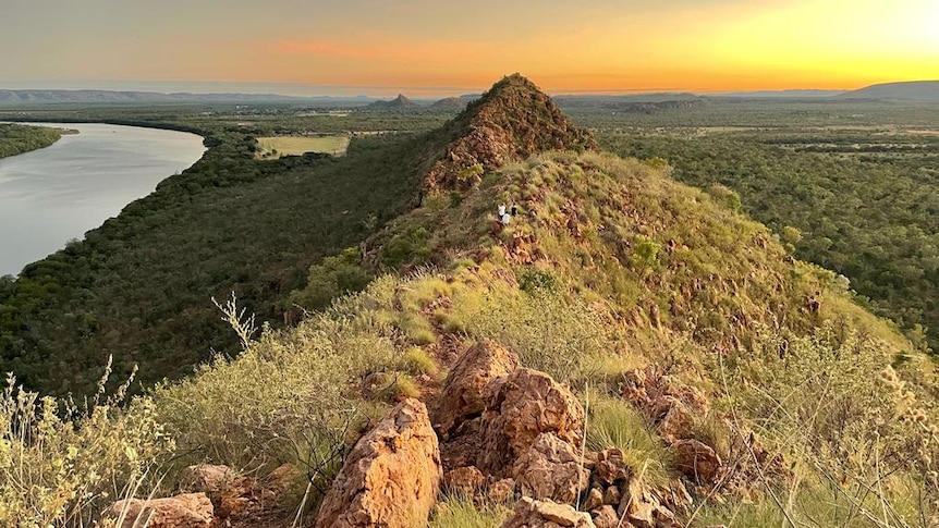 Morning sunlight hits red rock ridge as river bends in the distance