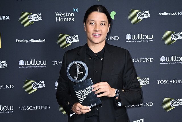 Soccer star Sam Kerr smiles as she holds a trophy after winning a big award.