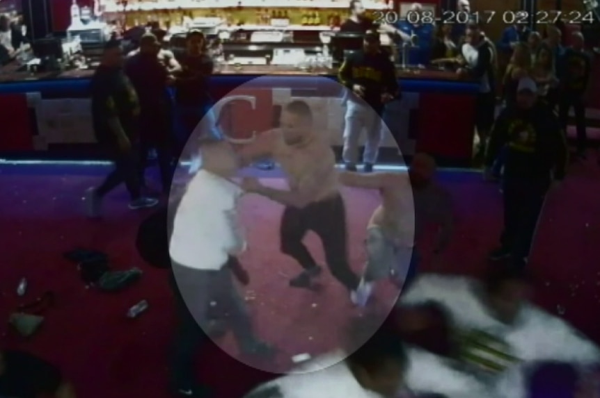 CCTV still of massive brawl at a strip club. One man is spotlighted.