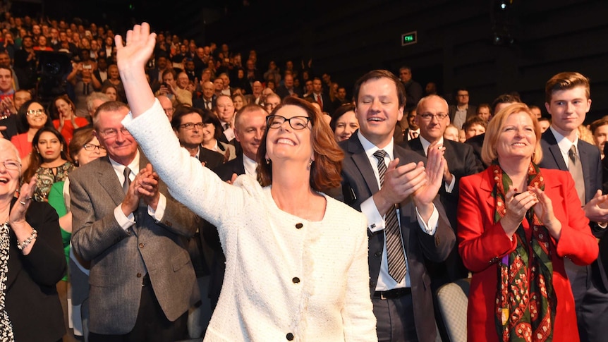 Julia Gillard holds up a hand and waves as she is cheered at the Labor election launch.