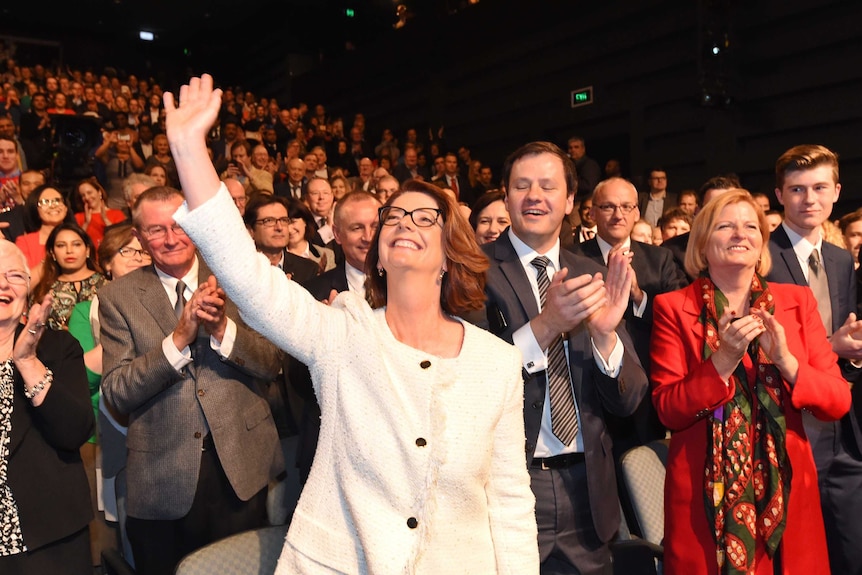 Julia Gillard holds up a hand and waves as she is cheered at the Labor election launch.