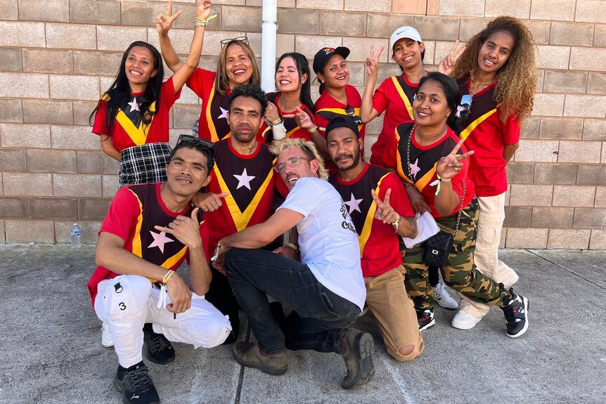 a white man with a big happy group of timorese people in matching shirts