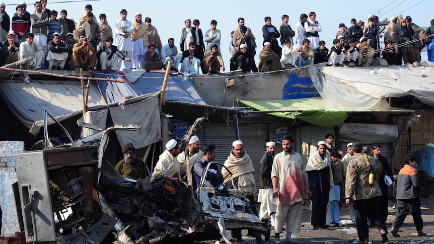 Pakistani locals gather at the site of a blast